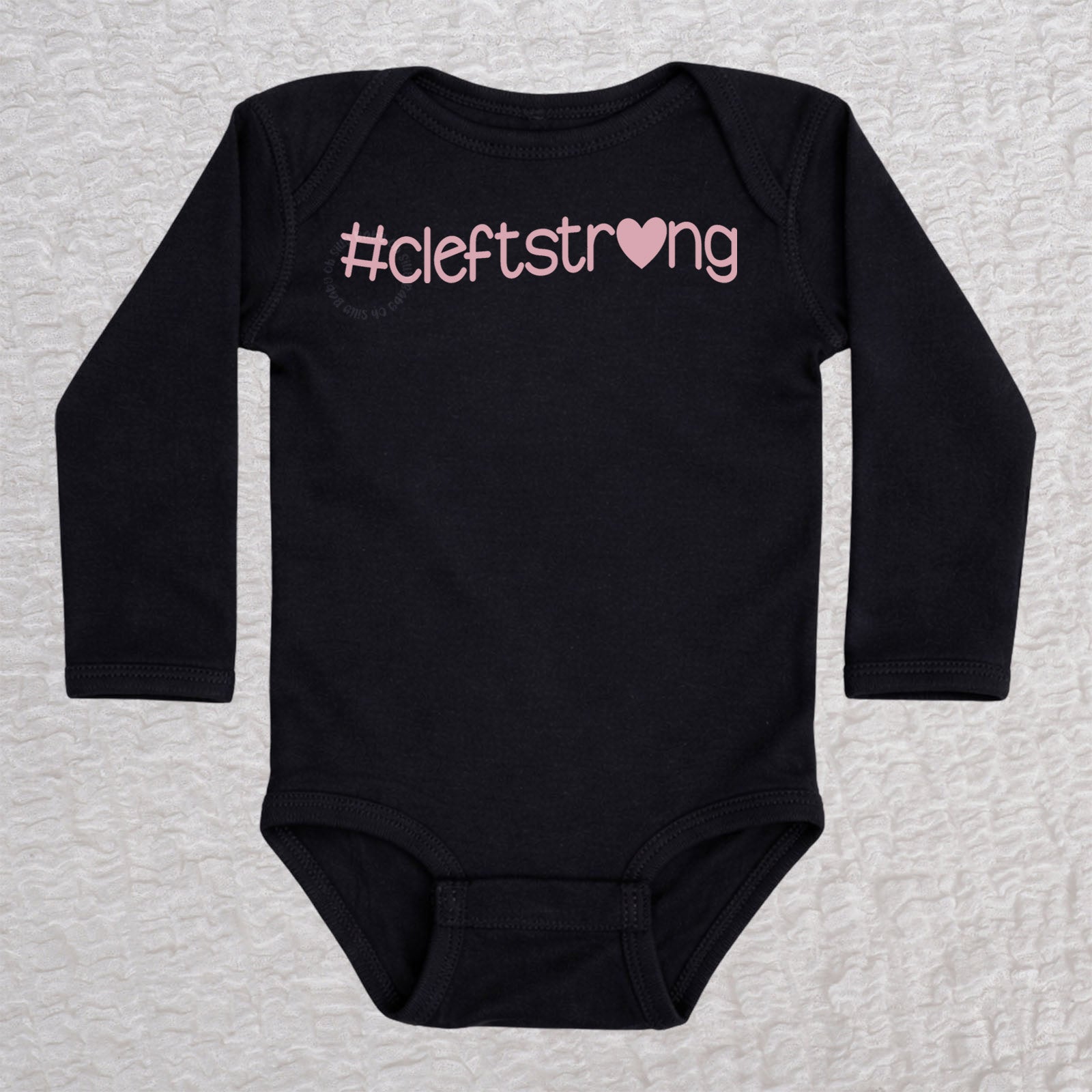 Cleftstrong Heart long sleeve baby bodysuit in black featuring a pink Cleftstrong heart design