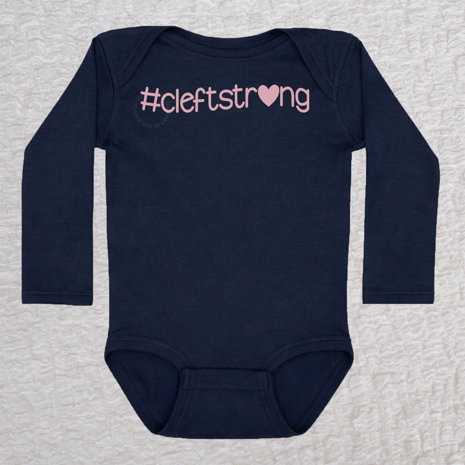 Cleftstrong Heart long sleeve baby bodysuit in navy featuring a pink Cleftstrong heart design