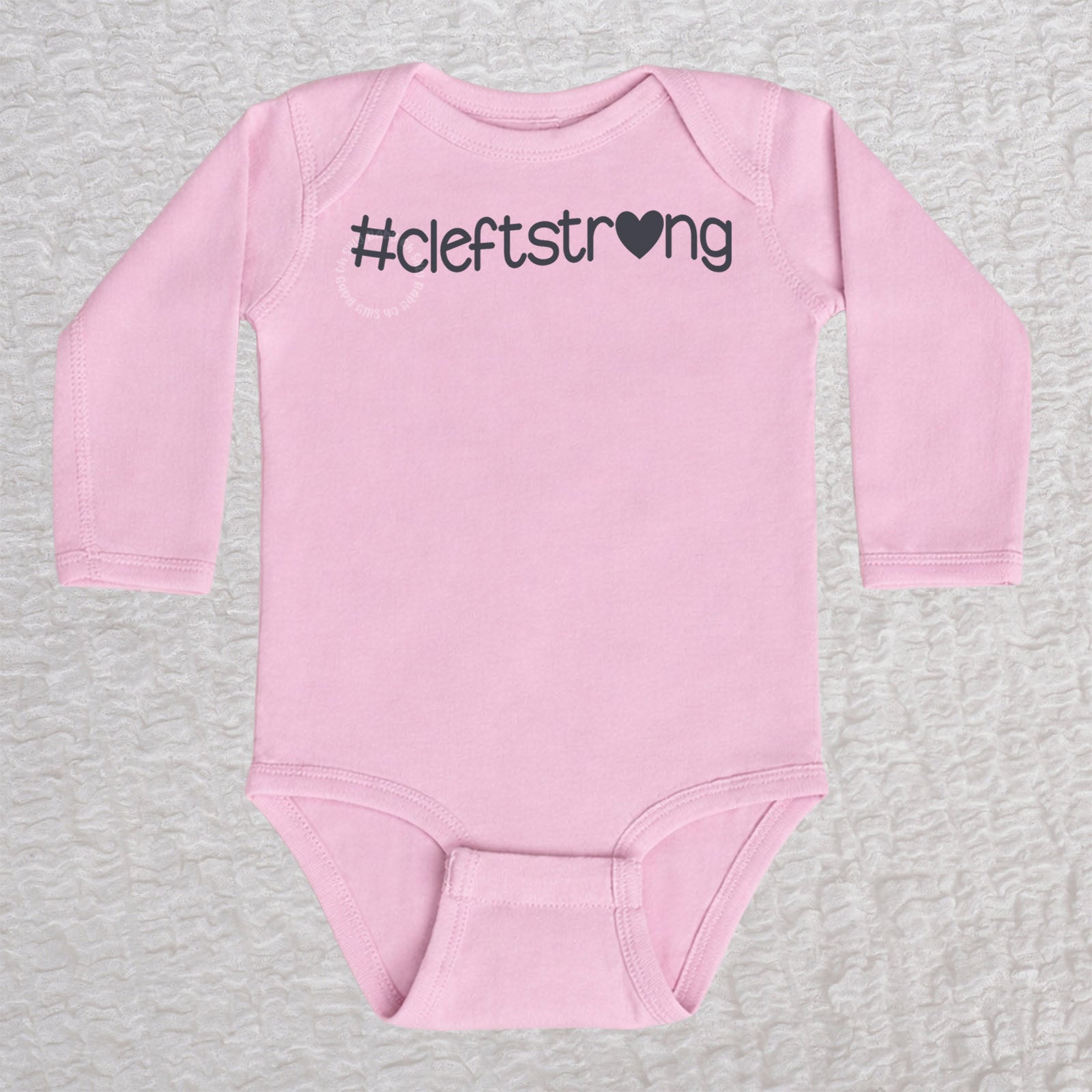 Cleftstrong Heart long sleeve baby bodysuit in pink featuring a pink Cleftstrong heart design