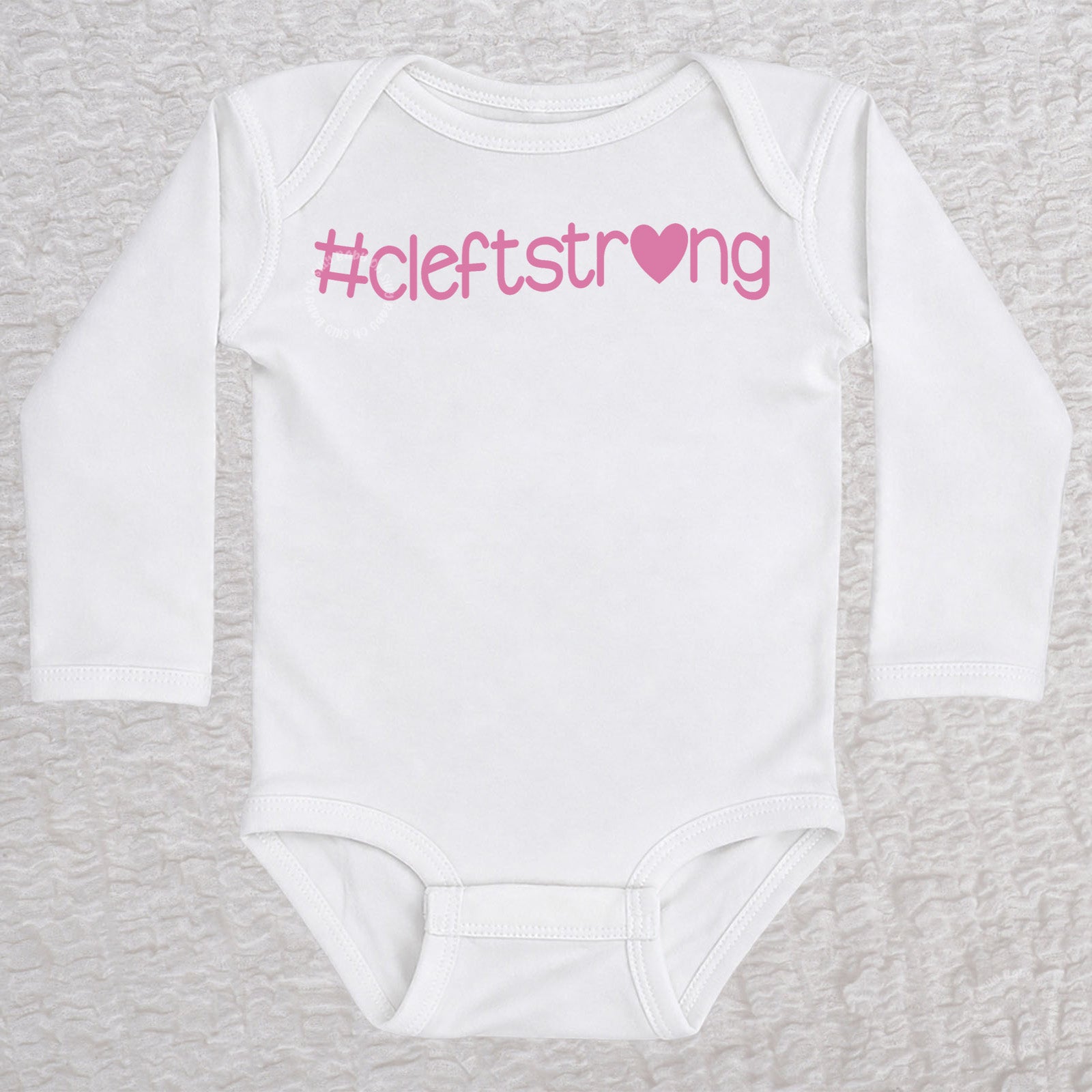 Cleftstrong Heart long sleeve baby bodysuit in white featuring a pink Cleftstrong heart design