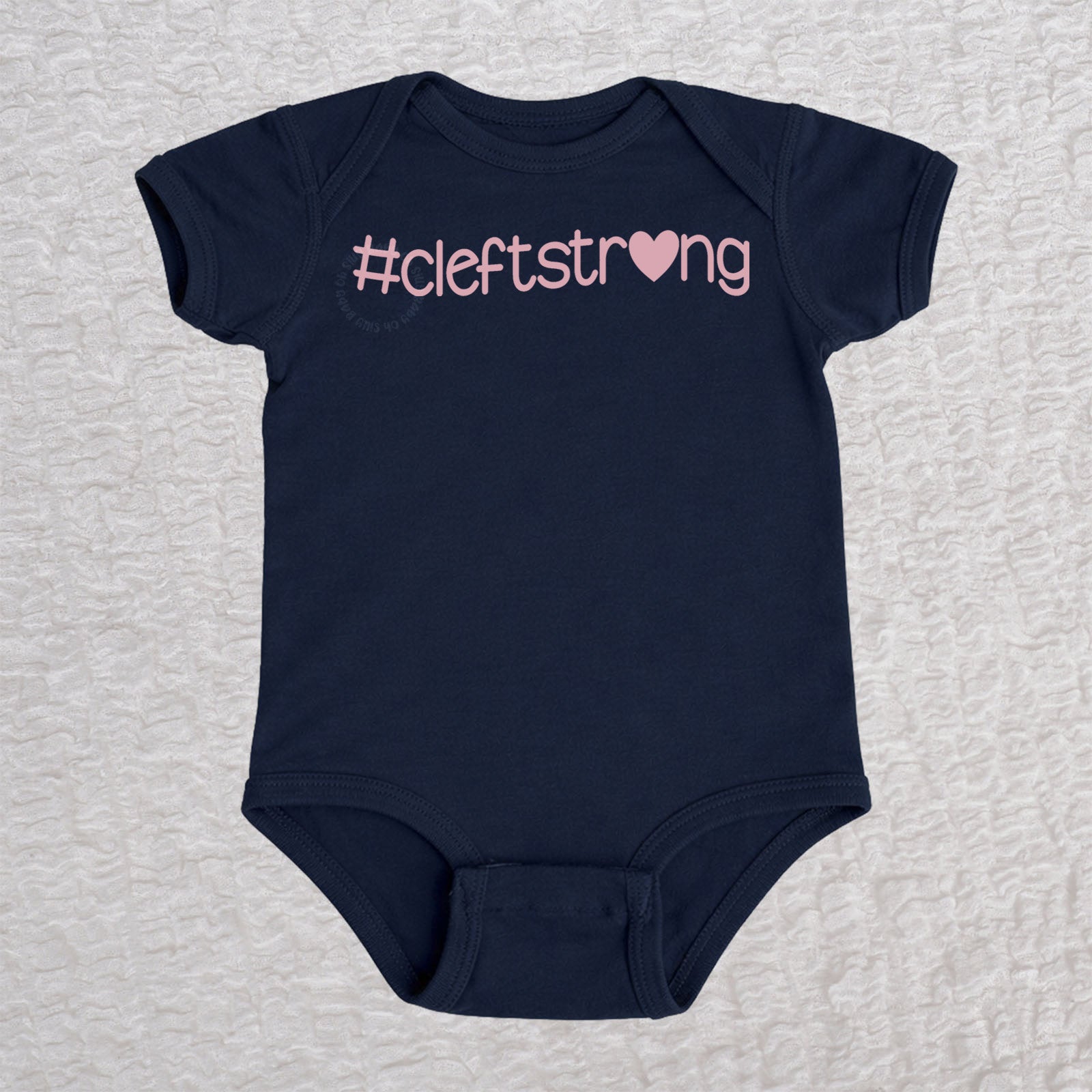 Cleftstrong Heart short sleeve baby bodysuit in navy featuring a pink Cleftstrong heart design