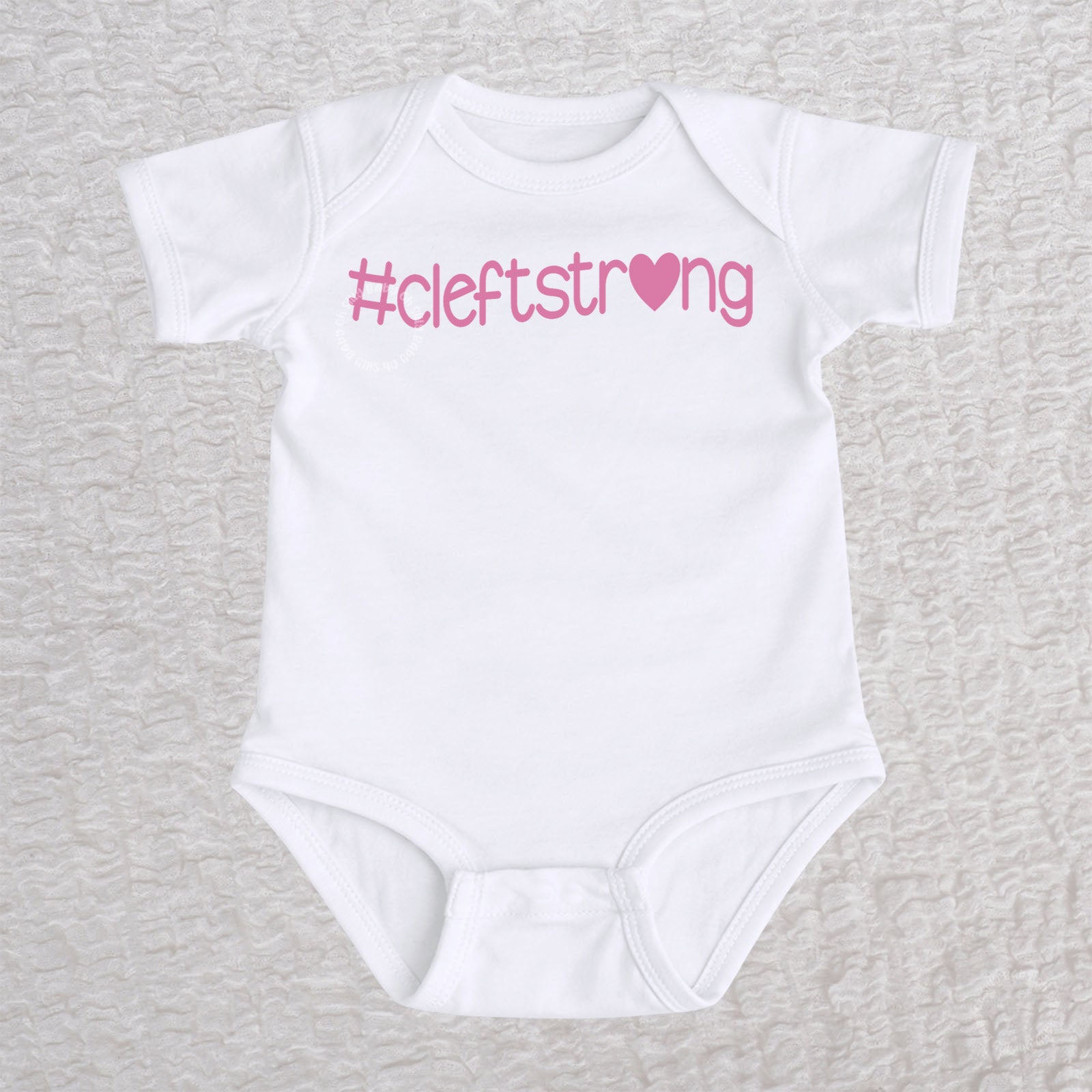 Cleftstrong Heart short sleeve baby bodysuit in white featuring a pink Cleftstrong heart design