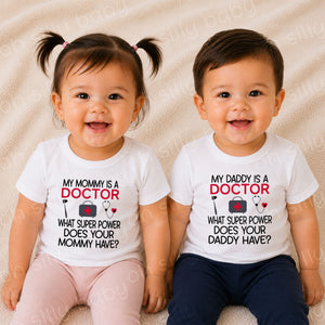 Toddlers wearing My Daddy Is a Doctor baby and toddler t-shirts featuring a medical bag, reflex hammer, and stethoscope design