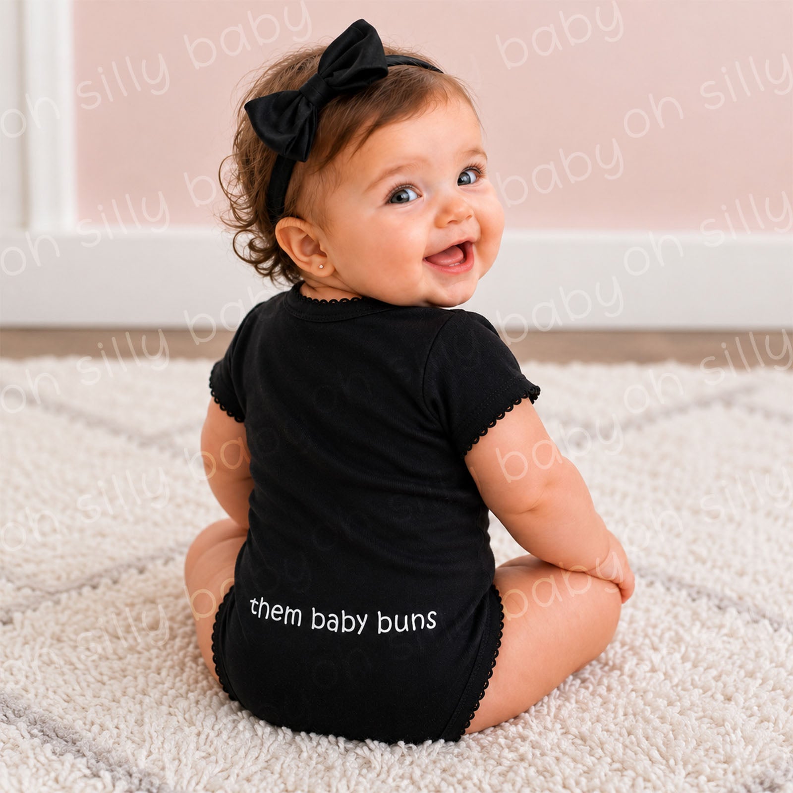 Baby girl showing the back of the I'm All About Them Buns black baby bodysuit with the them baby buns design