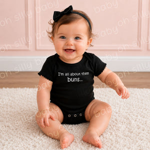 Baby girl wearing the I'm All About Them Buns black baby bodysuit