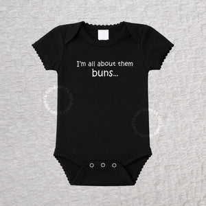 Black baby bodysuit with the funny saying I'm All About Them Buns on the front