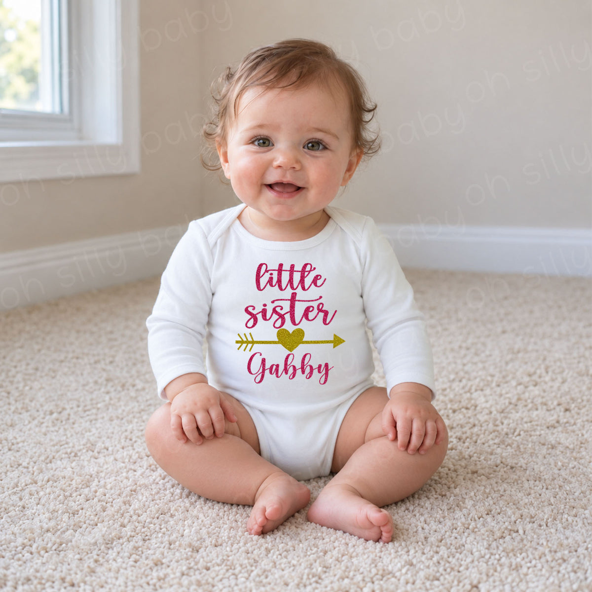 Little Sister Elegant Script baby wearing white long sleeve bodysuit with pink glitter lettering, gold glitter heart arrow and personalized name