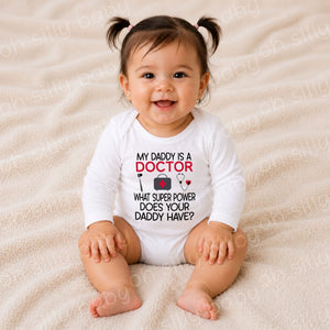 Baby wearing a My Daddy Is a Doctor long sleeve baby bodysuit featuring a reflex hammer, medical bag, and stethoscope design