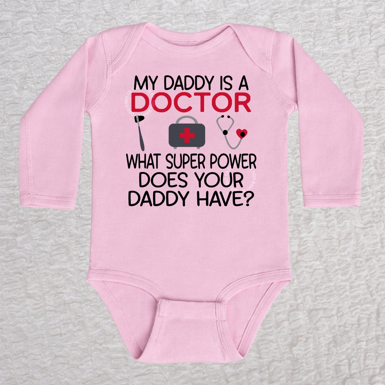 My Daddy Is a Doctor long sleeve baby bodysuit in pink featuring a reflex hammer, doctor's bag, and stethoscope design