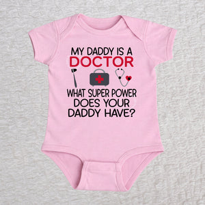 My Daddy Is a Doctor short sleeve baby bodysuit in pink featuring a reflex hammer, doctor's bag, and stethoscope design