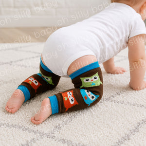 Baby crawling in a white short sleeve bodysuit wearing Owl baby leg warmers