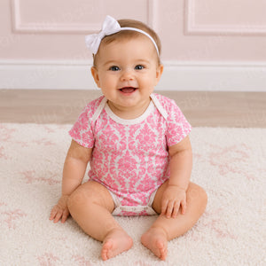Baby girl wearing a Pink Damask Print baby bodysuit made from 100% cotton interlock knit fabric