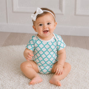 Baby wearing a turquoise and white Quatrefoil Print baby bodysuit