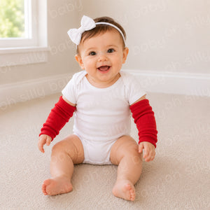 Baby girl wearing red baby leg warmers as arm warmers with a white baby bodysuit