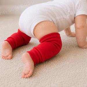 Close-up of a crawling baby wearing red baby leg warmers with a white baby bodysuit